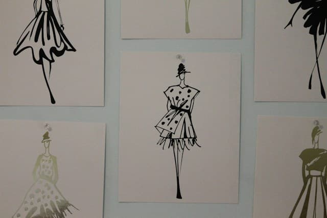 Fashion illustrations of elegant dress designs displayed on a wall