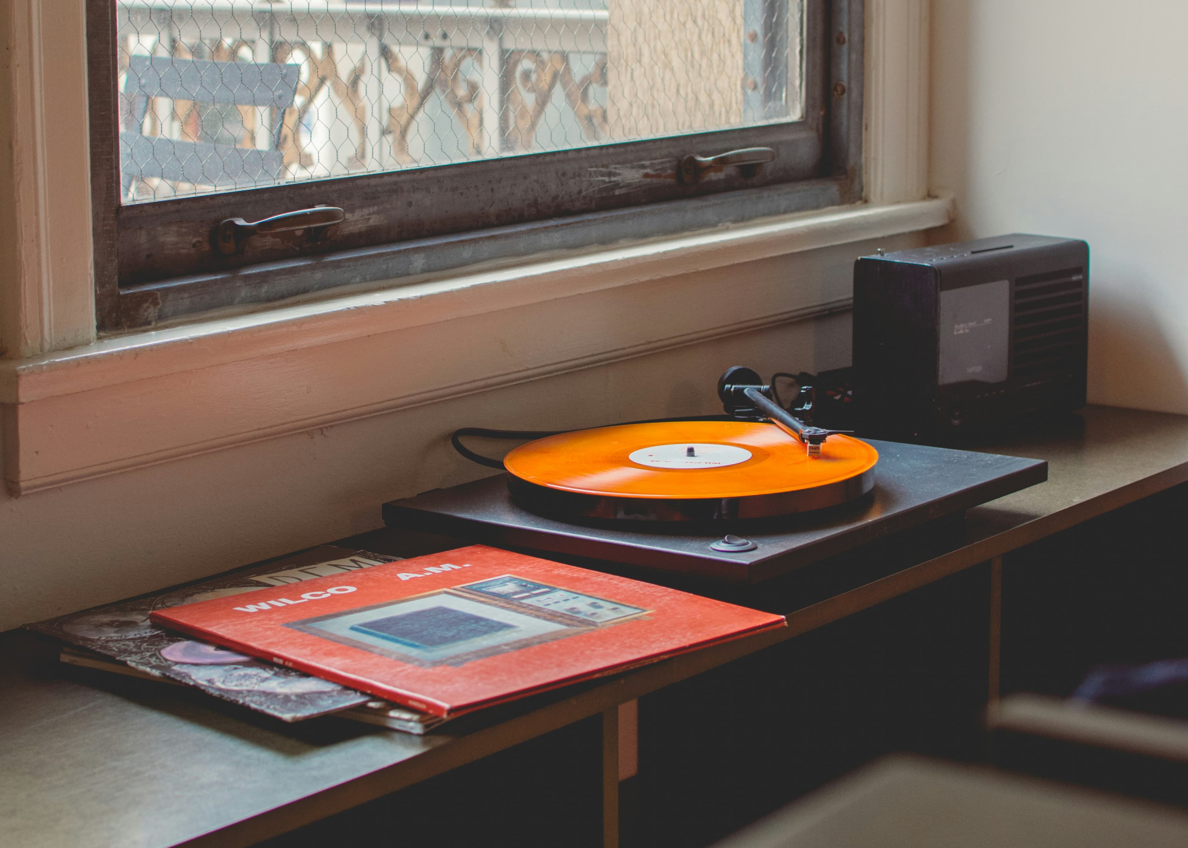 A turntable and records beside a window at a hotel
