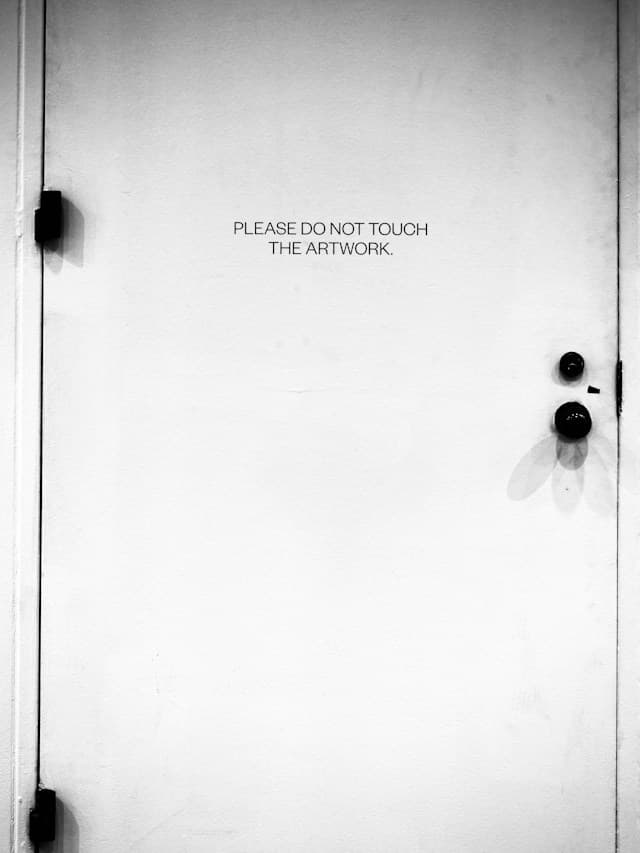 A white museum door bearing a notice asking visitors not to touch the artwork.