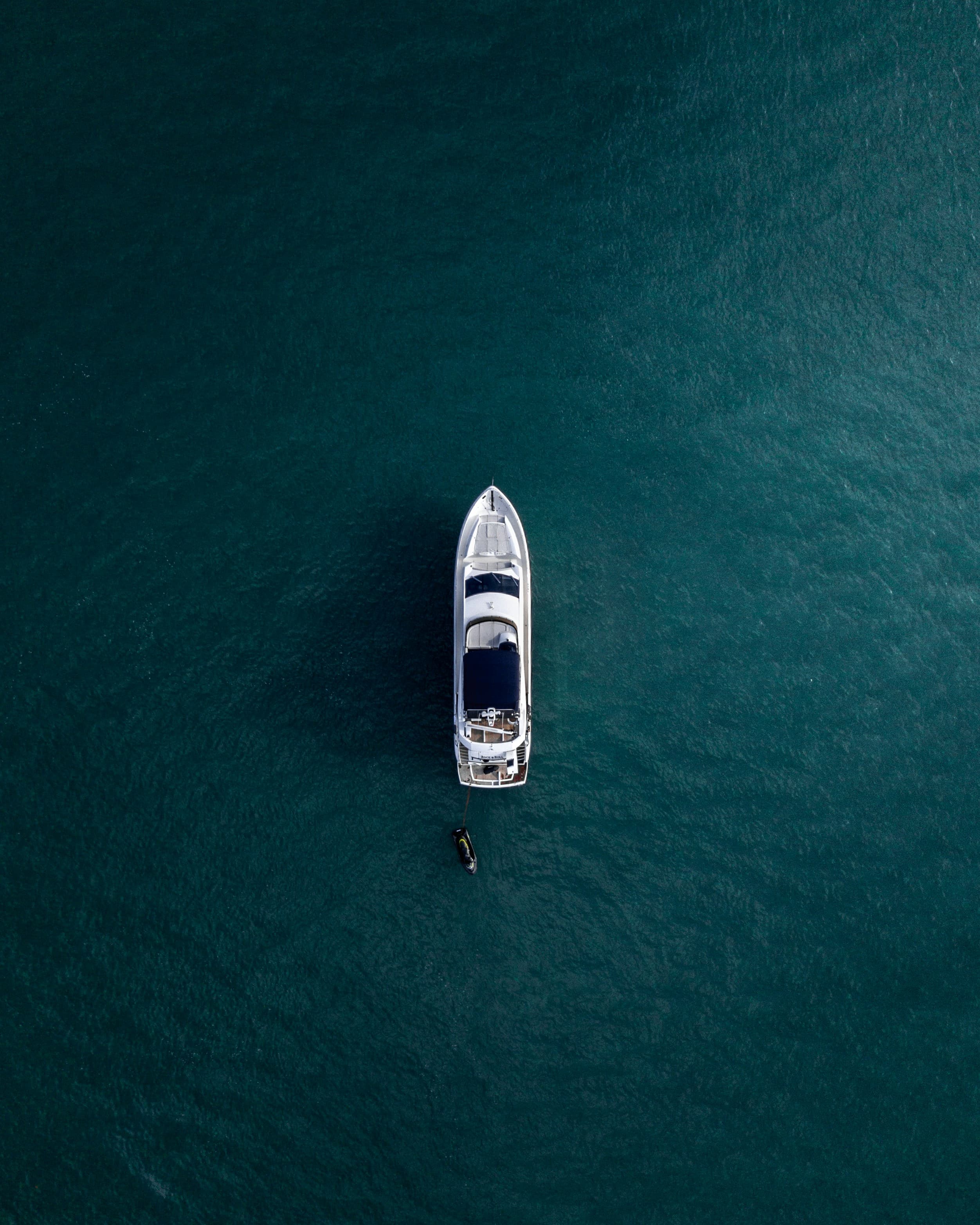 A solitary white yacht photographed from above on calm blue water